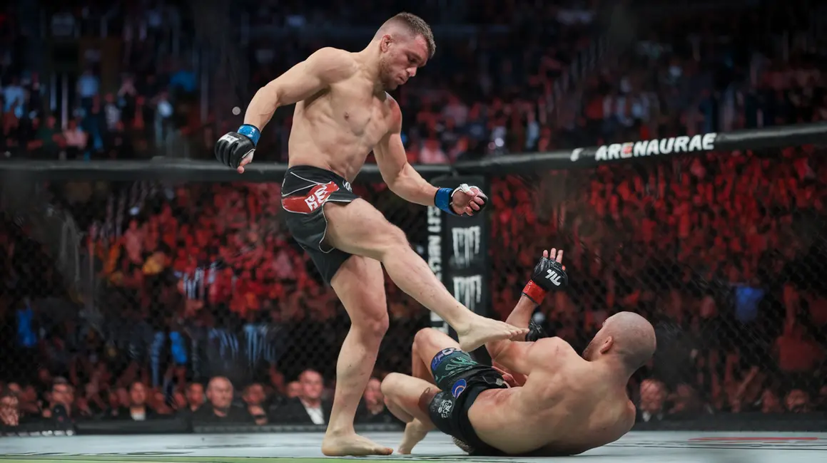 Akcja MMA z zawodnikami łączącymi techniki stójkowe i parterowe w oktagonie