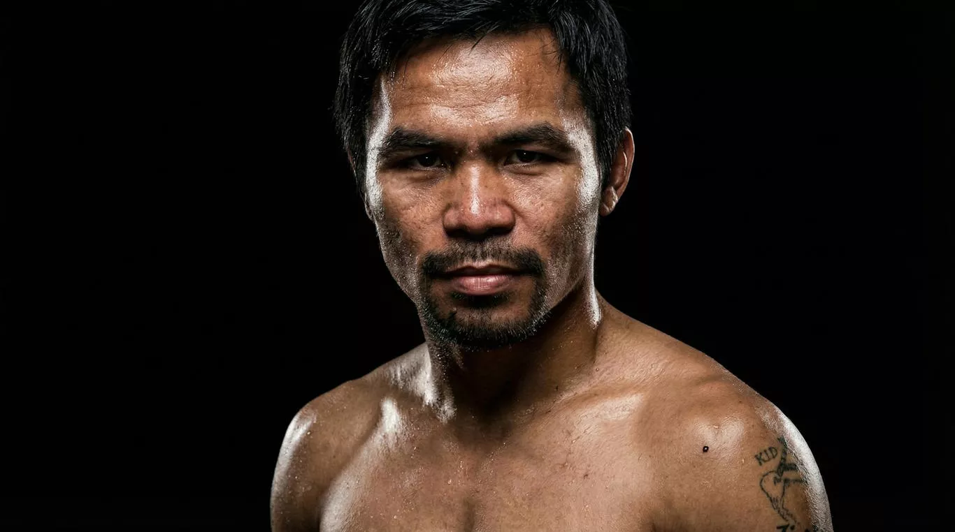 Nie rozpoznaję osoby na obrazie. Mężczyzna patrzy intensywnie przed siebie, mając odkryte, umięśnione ramiona. Tło jest ciemne, co podkreśla jego sylwetkę i wyraz twarzy.