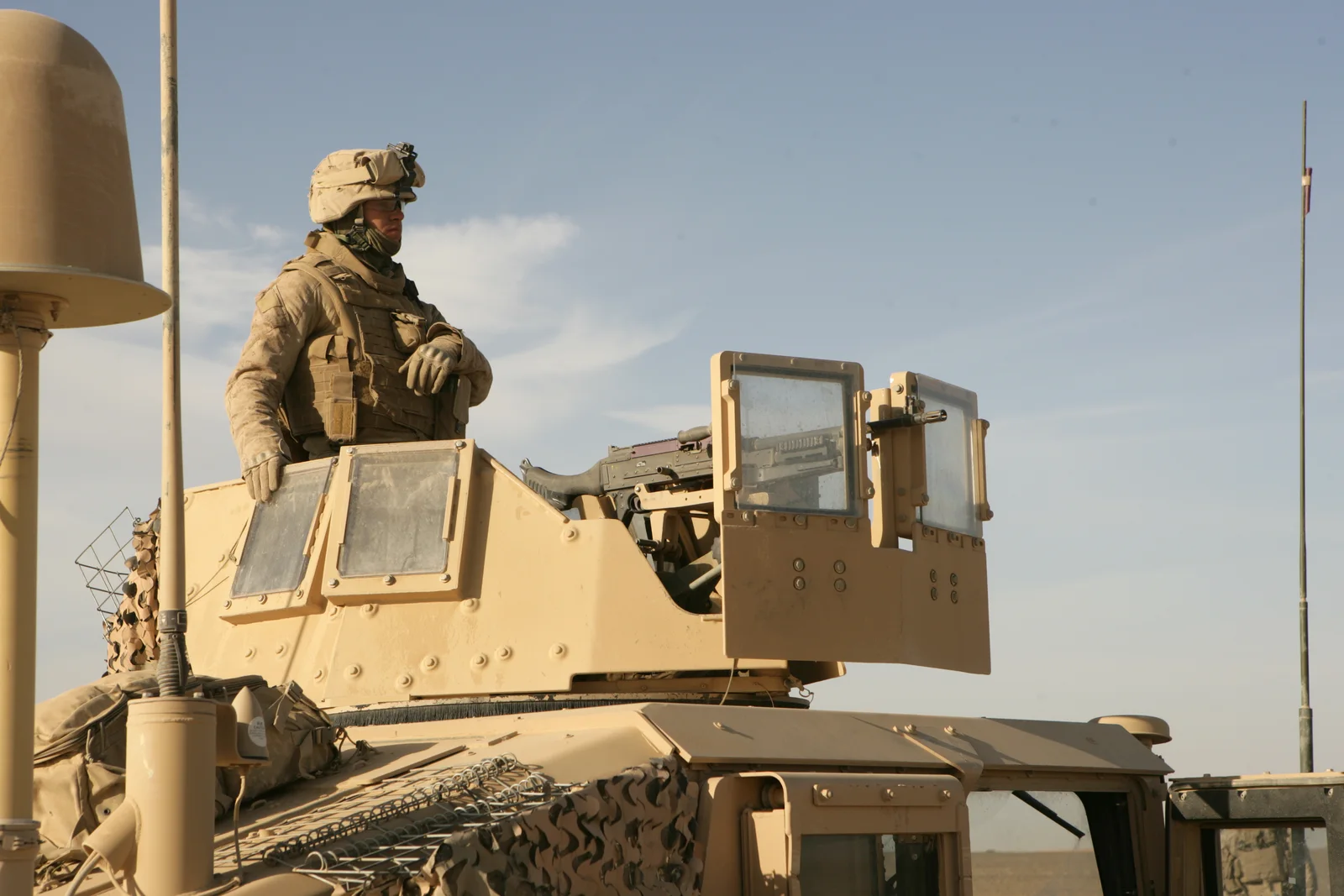 Żołnierz piechoty morskiej USA w wieżyczce opancerzonego Humvee z karabinem maszynowym M240 osłoniętym pancernymi tarczami z szybami