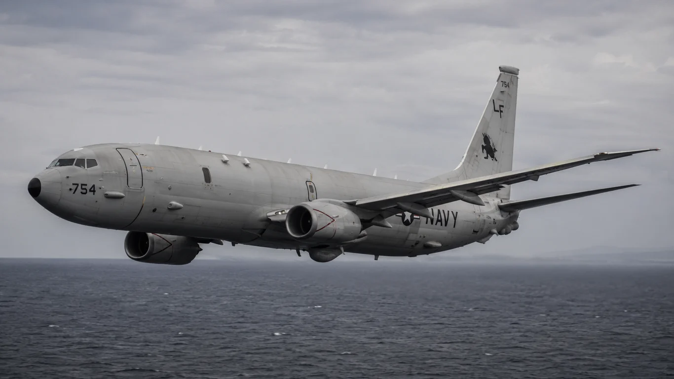Boeing P-8 Poseidon US Navy w locie nad oceanem, z otwartą komorą uzbrojenia i widocznymi wyrzutniami pław hydroakustycznych w tylnej części kadłuba.