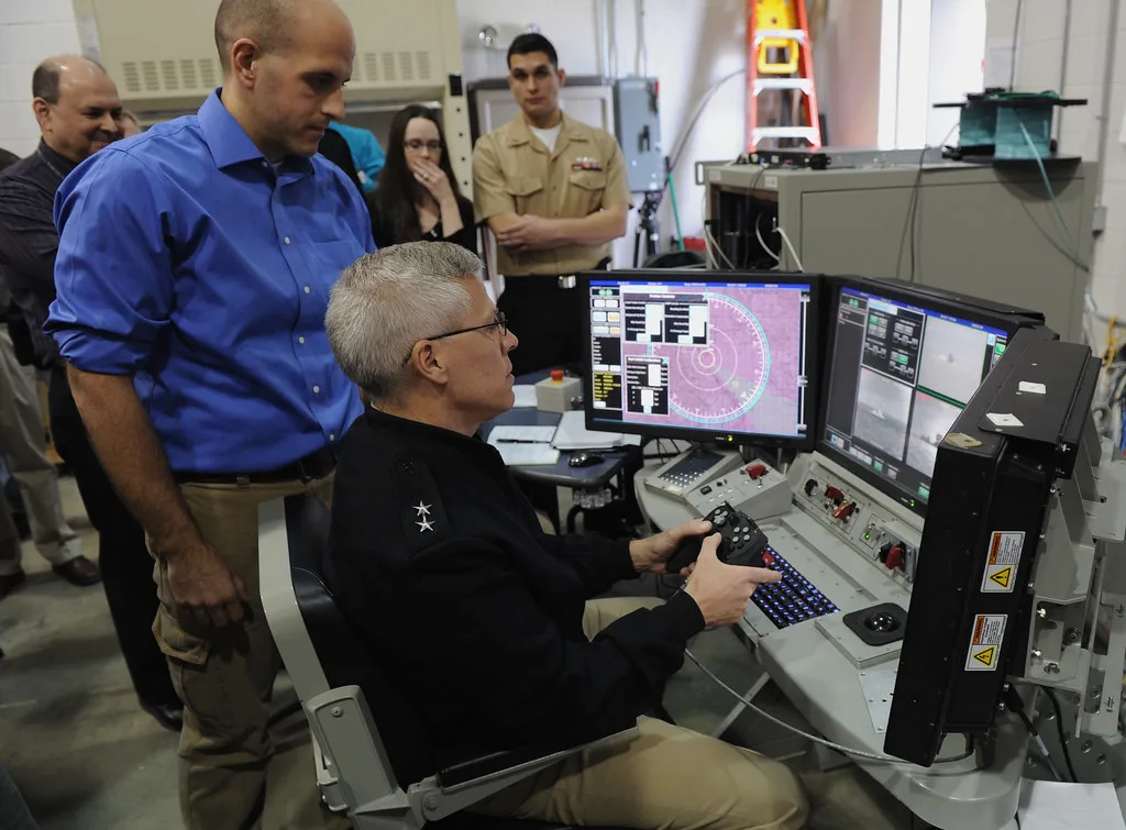 Operator przy konsoli sterowania morskim systemem laserowym US Navy z monitorami i joystickiem
