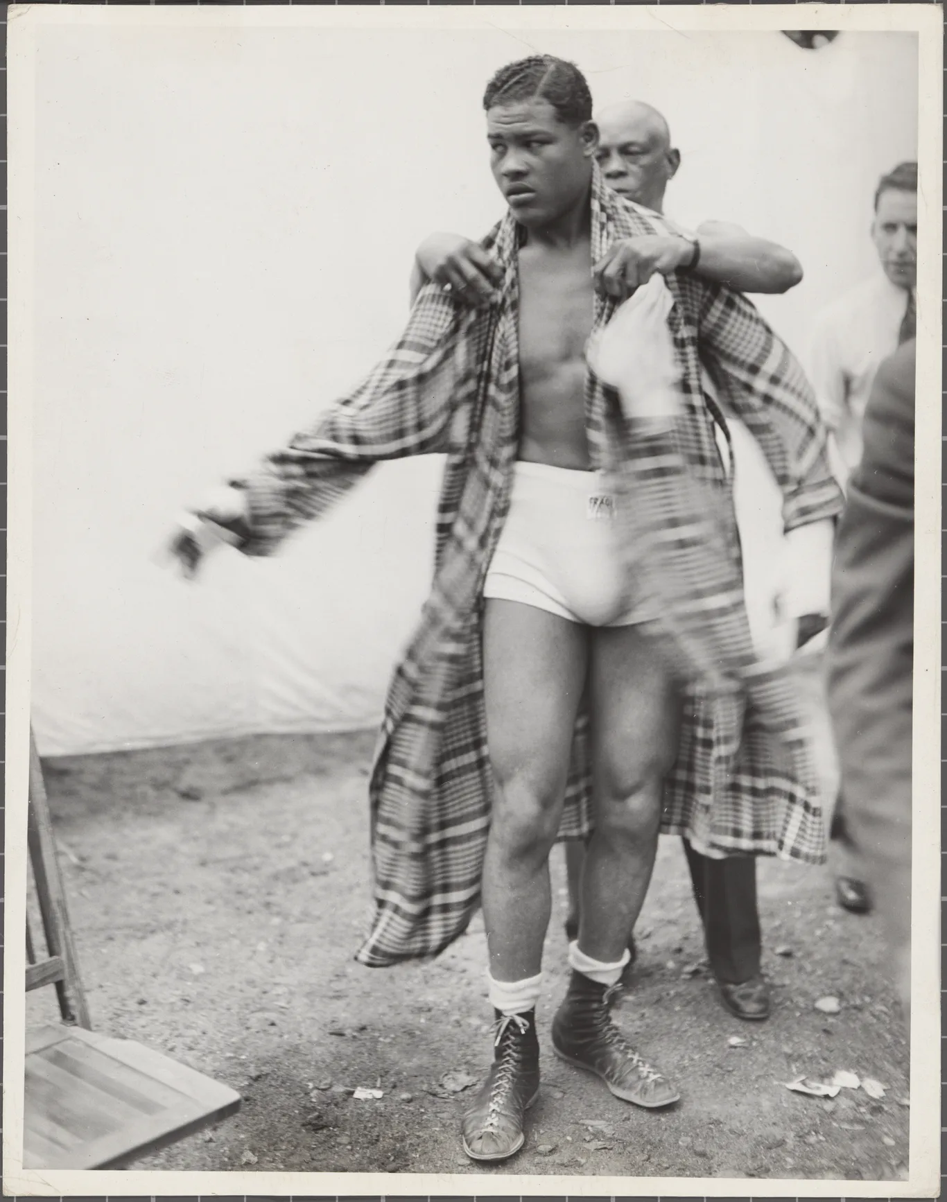 Joe Louis w bokserskim stroju zakłada szlafrok za kulisami walki
