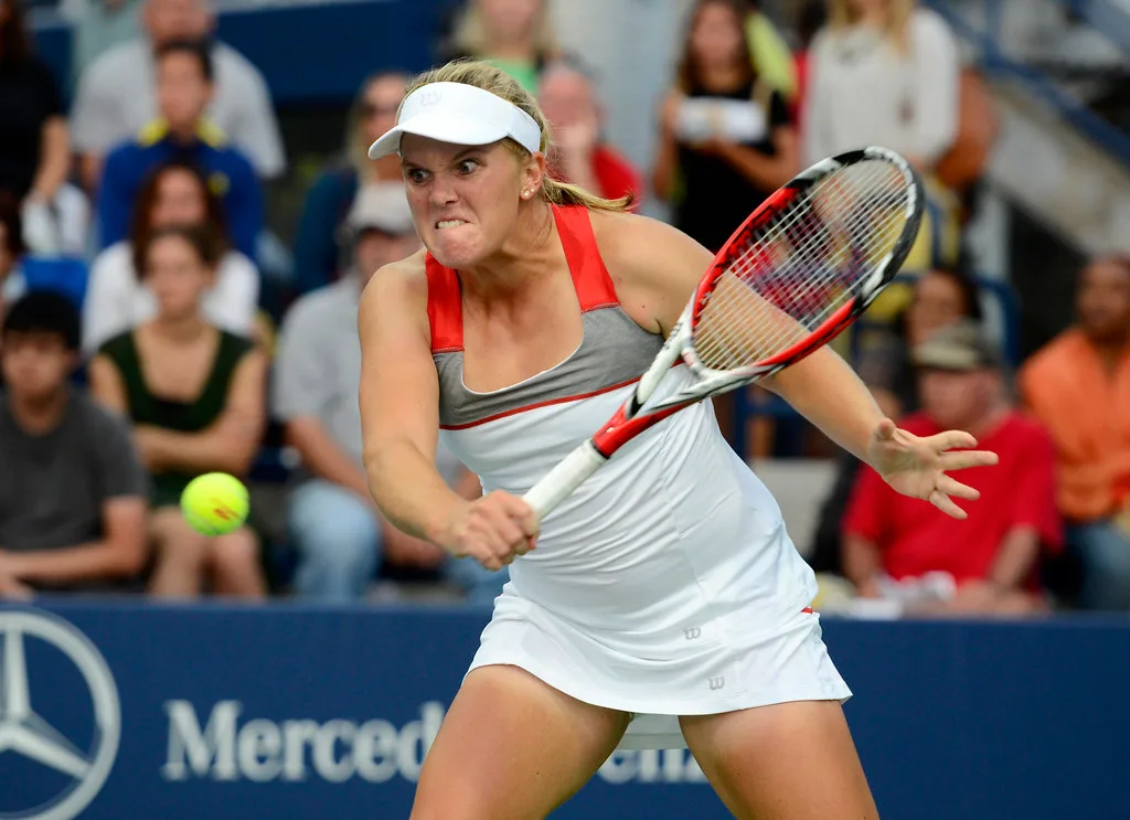 Tenisistka wykonuje forehand z wyprostowanym stawem łokciowym, trzymając rakietę