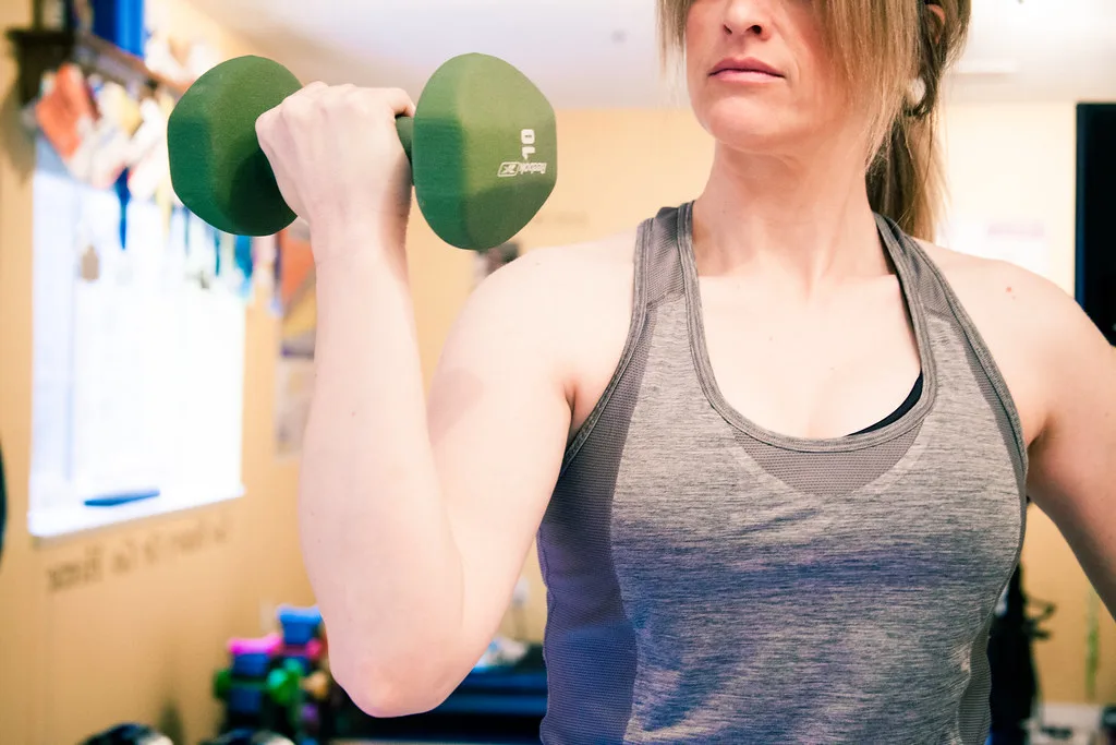 Kobieta wykonuje uginanie ramienia z hantlem – ćwiczenie na biceps