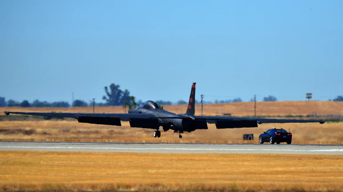 Lockheed U-2 tuż nad pasem startowym, obok jadący równolegle samochód pościgowy.