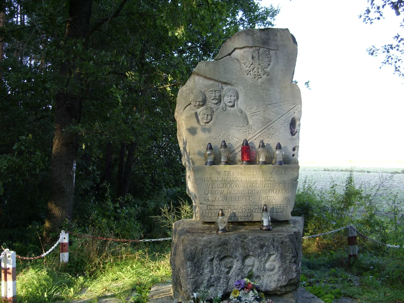 Kamienny pomnik z godłem Polski i płaskorzeźbą rodziny, upamiętniający Polaków zamordowanych przez UPA w Bełżcu