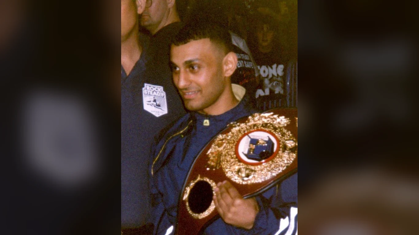 Naseem Hamed z pasem mistrzowskim WBO przewieszonym przez ramię, w otoczeniu kibiców