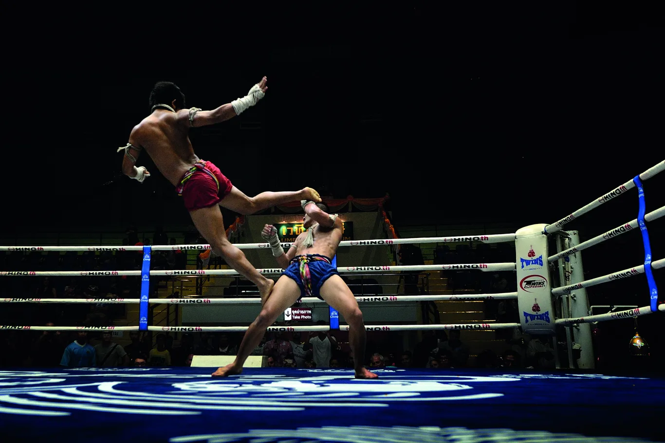 Walka muay thai na ringu stadionu Lumpinee w Bangkoku – zawodnik wyprowadza wysokie kopnięcie